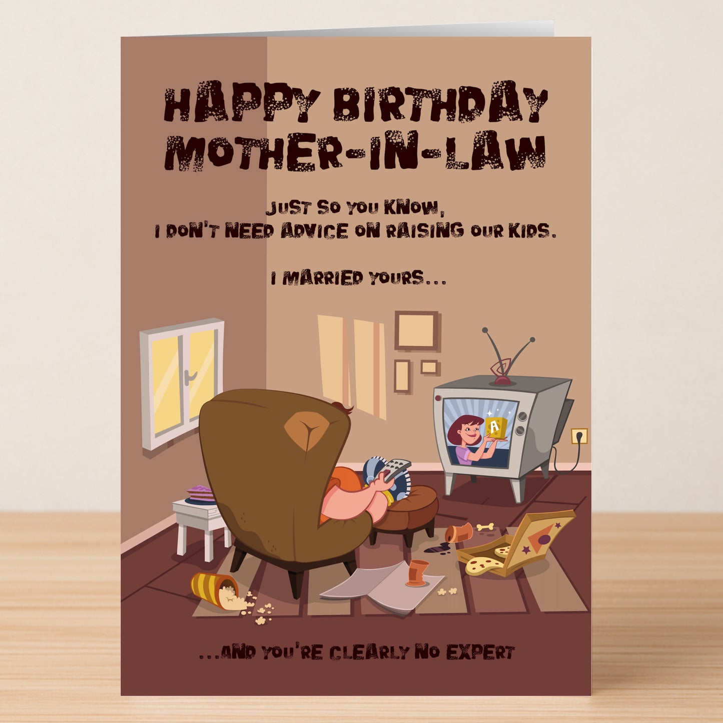 Twisted Gifts' No Expert – Insulting Birthday Card features the message: "Happy Birthday Mother-in-Law. I married your kid, so clearly you’re no expert!"—a hilarious card shown in a messy living room, perfect for those who love edgy humor.