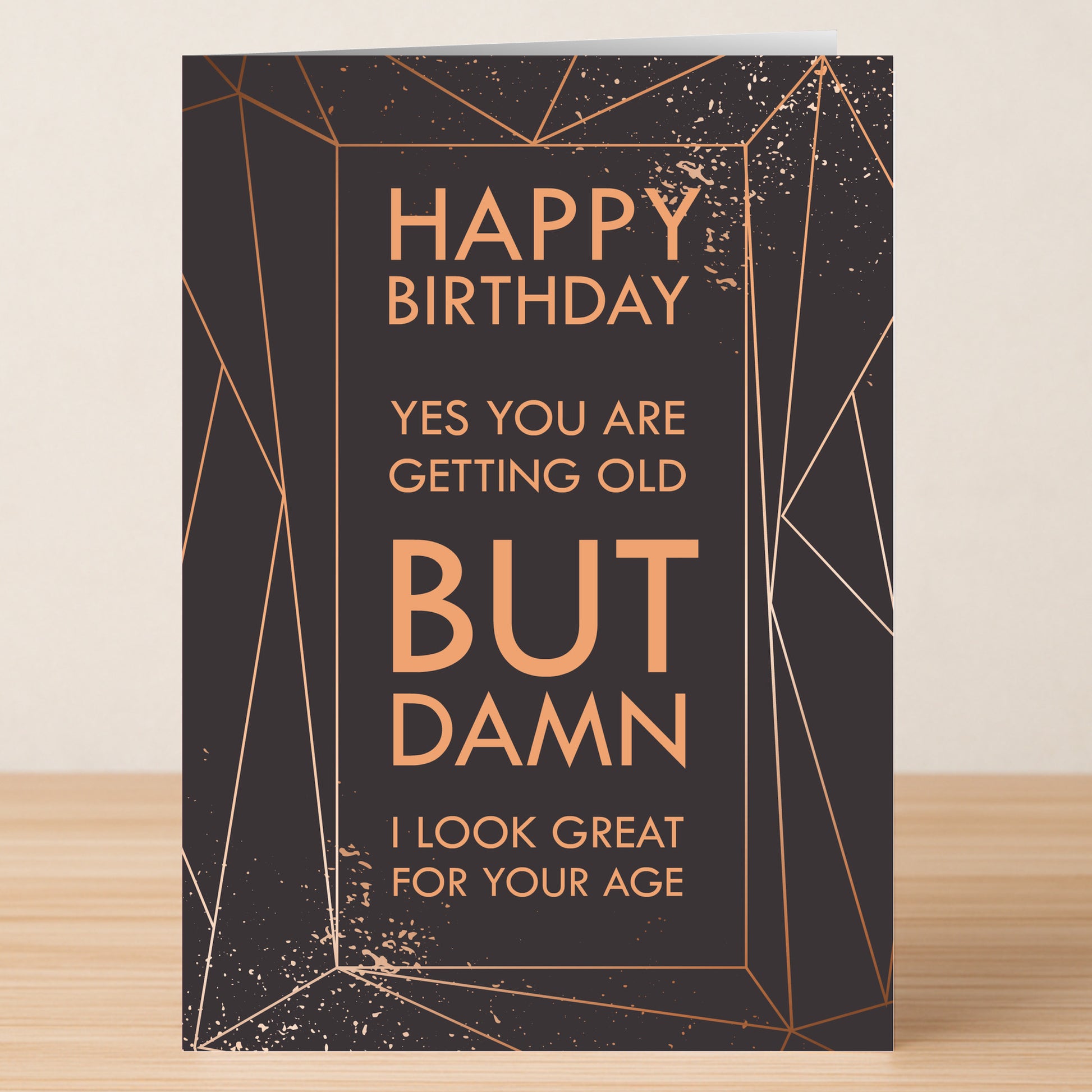 The Looking Good – Funny Birthday Card by Twisted Gifts features geometric gold lines on black and the message: "Happy Birthday. Yes you are getting old BUT DAMN I look great for your age.