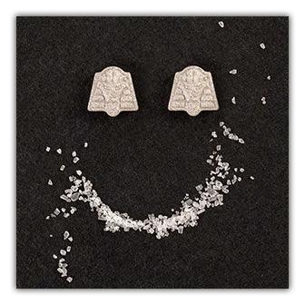 A pair of Twisted Gifts Pharoah Coaster earrings with a smiley face on them.
